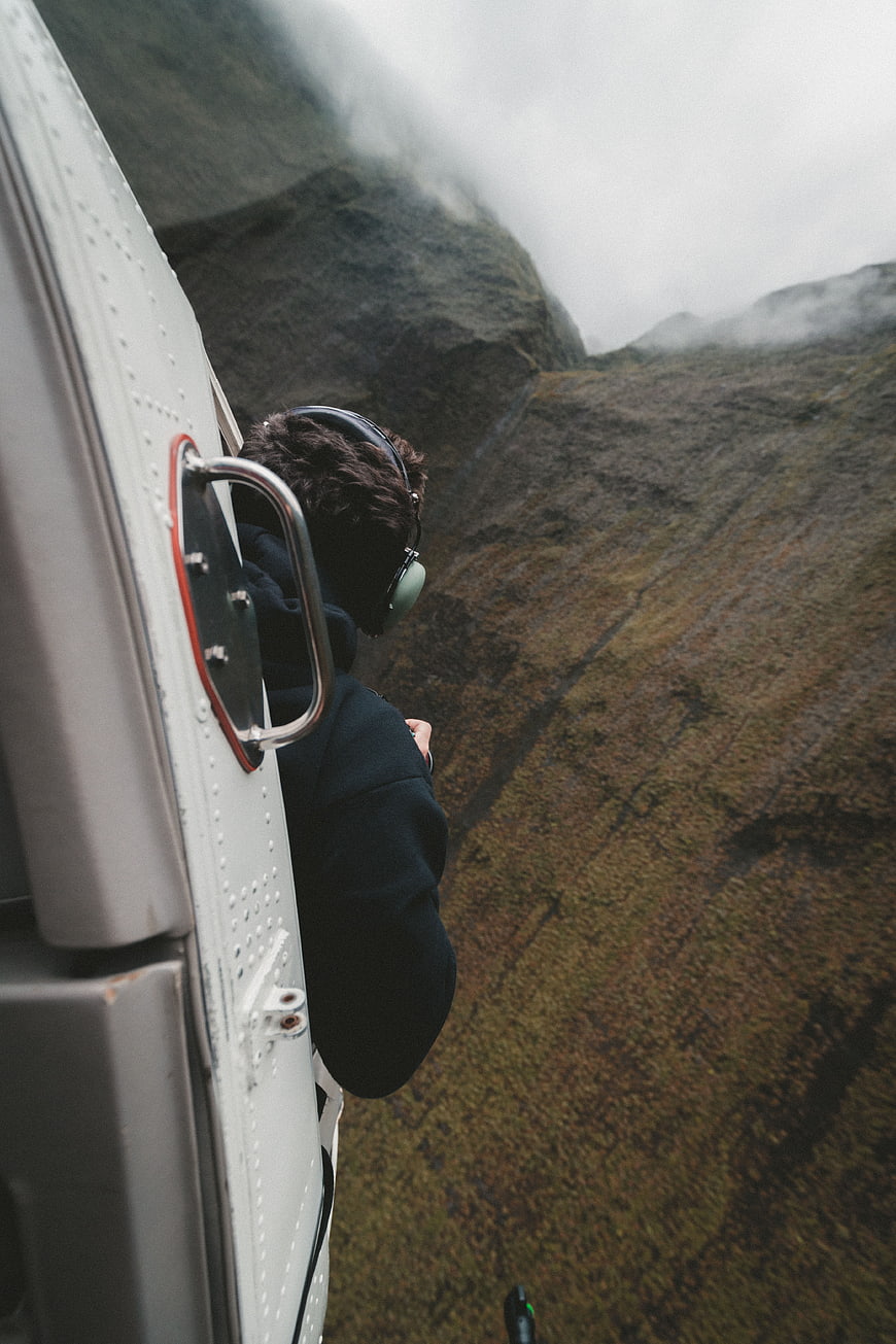 Man leaning out of helicopter window over foggy mountains
