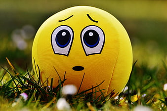 Yellow Emoji Ball with Sad Face in Green Grass