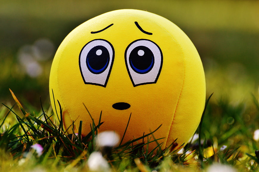 Yellow Emoji Ball with Sad Face in Green Grass