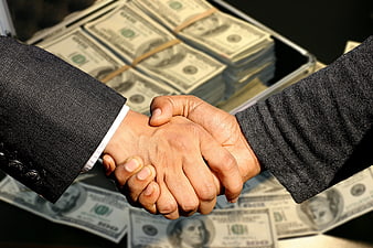 Business handshake over stacks of US dollar bills in briefcase