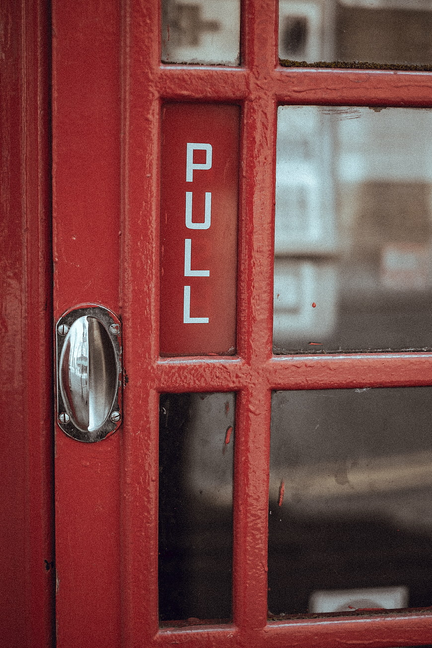 Close-up of red telephone booth door with pull handle