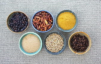 Assorted Spices In Ceramic Bowls On Textured Fabric