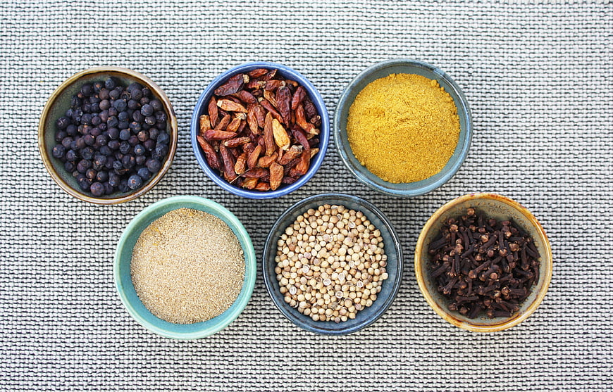Assorted Spices In Ceramic Bowls On Textured Fabric