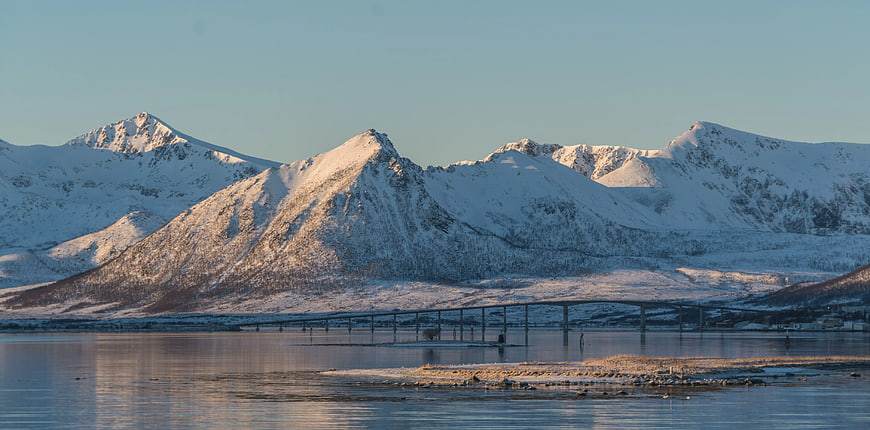 Snow-Covered Mountains and Bridge Over Calm Water