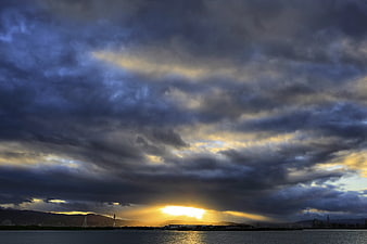 Dramatic Sunset with Nimbus Clouds Over Water and Cityscape