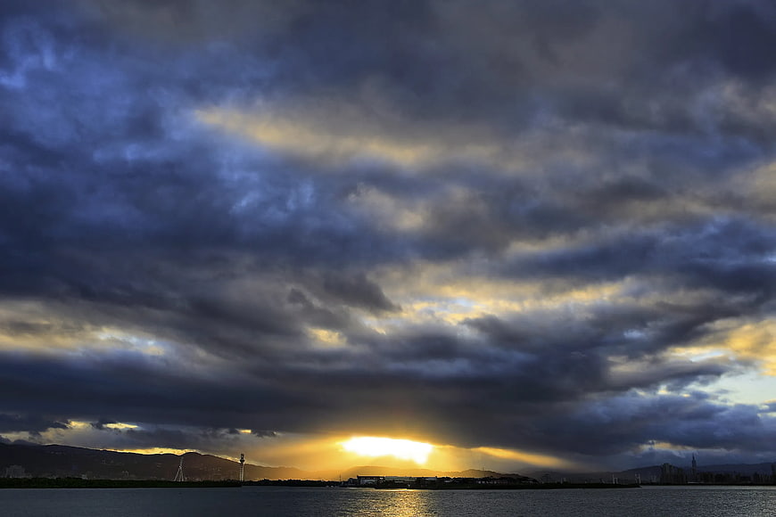Dramatic Sunset with Nimbus Clouds Over Water and Cityscape