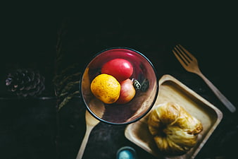 Top view of fruit bowl and croissant on dark table