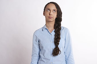 Young woman with long braid looking up with bored expression