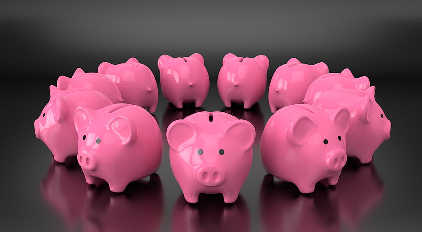 Group of pink ceramic piggy banks on dark reflective surface