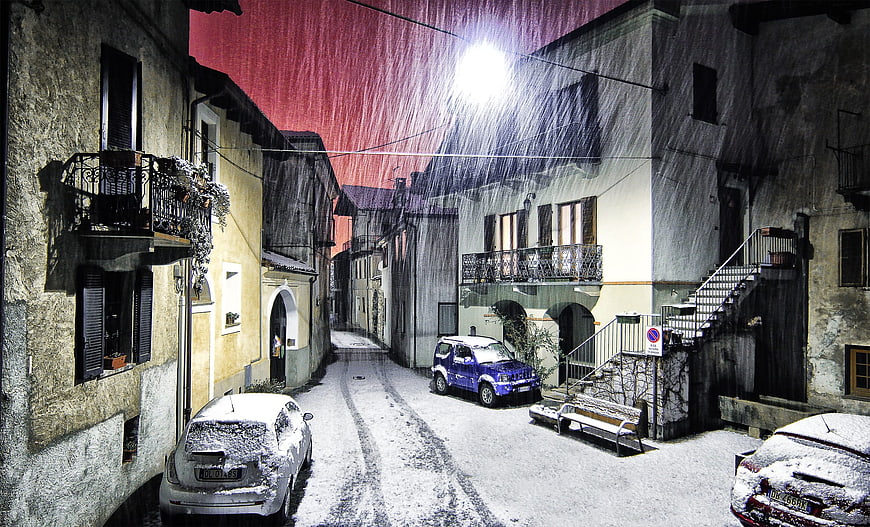 Snowy Night Street in Italian Village with Red Sky