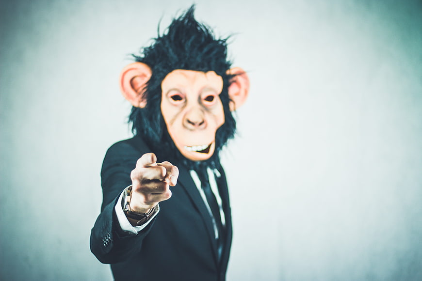 Man in Monkey Mask Pointing Finger in Business Suit