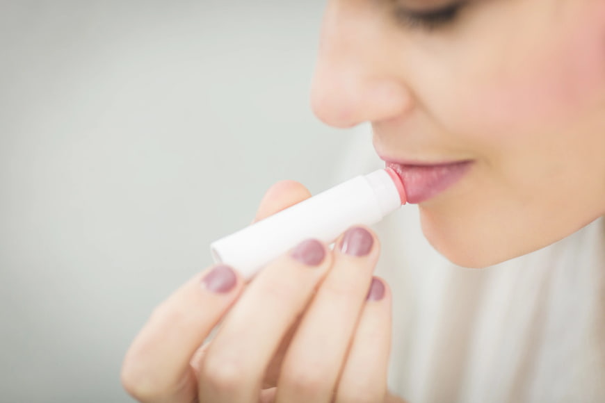 Close-up of woman applying pink lip balm