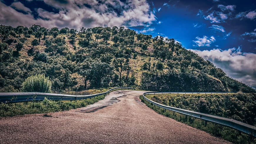 Winding Mountain Road Through Green Hills Under Blue Sky