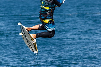 Kitesurfer mid-air jump over blue ocean water