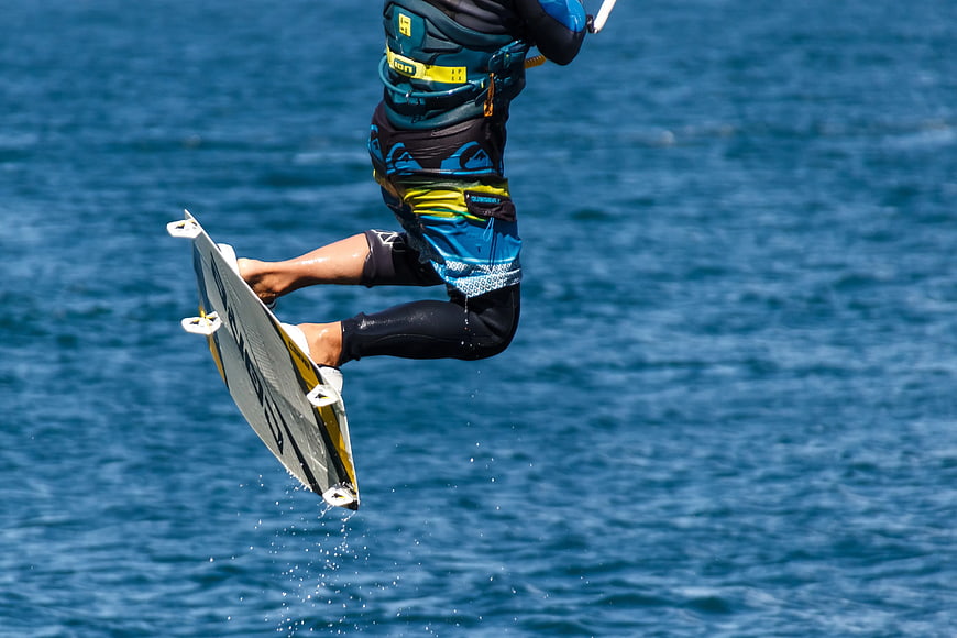 Kitesurfer mid-air jump over blue ocean water