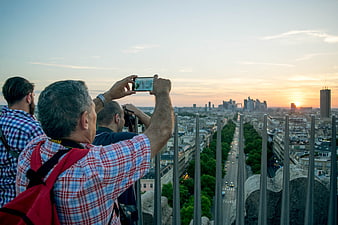 Tourists photographing Paris cityscape at sunset from Eiffel Tower