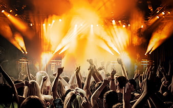 Energetic crowd at a concert with bright orange stage lights
