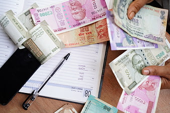 Indian Rupee Banknotes, Notebook, and Pen on Wooden Desk