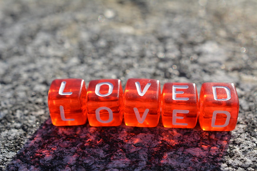 Red Dice Spelling Loved on Textured Surface