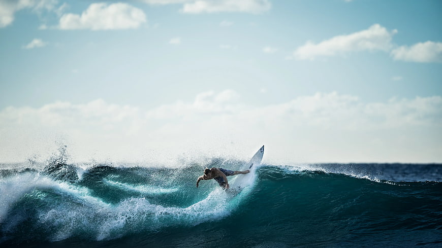Surfer Riding a Wave on a White Surfboard