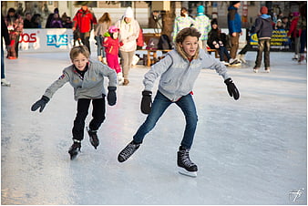 Two boys ice skating at outdoor winter rink