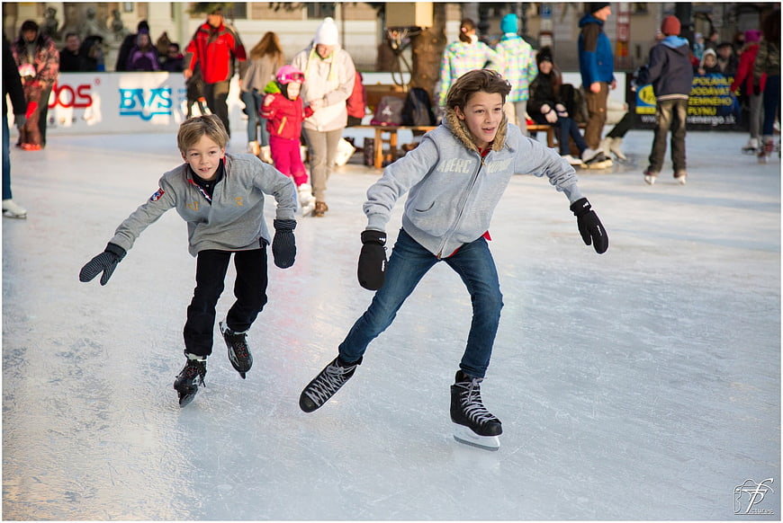 Two boys ice skating at outdoor winter rink