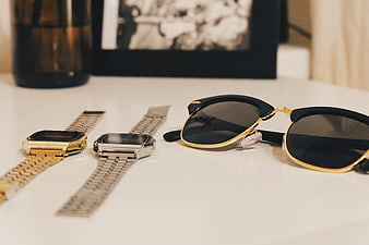 Vintage gold and silver watches with sunglasses on white table