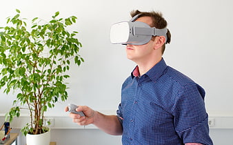 Man Wearing VR Headset Holding Controller In Office