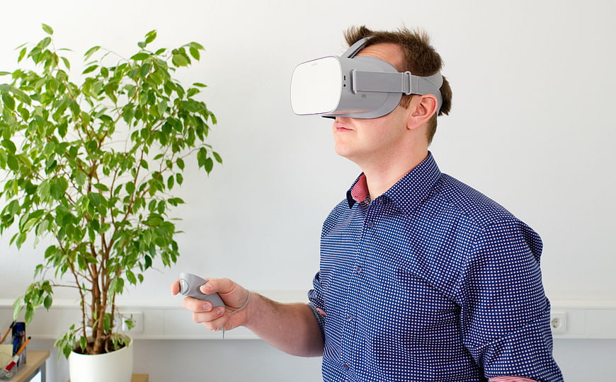Man Wearing VR Headset Holding Controller In Office