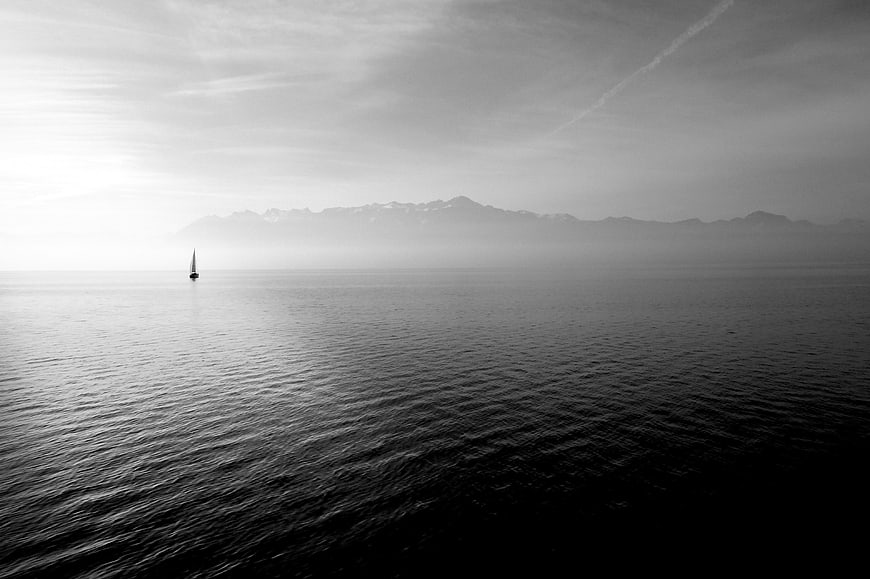Solitary Sailboat on Calm Black and White Lake