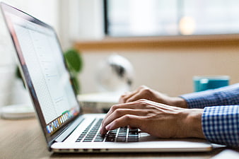 Close-up of hands typing on a laptop keyboard in office