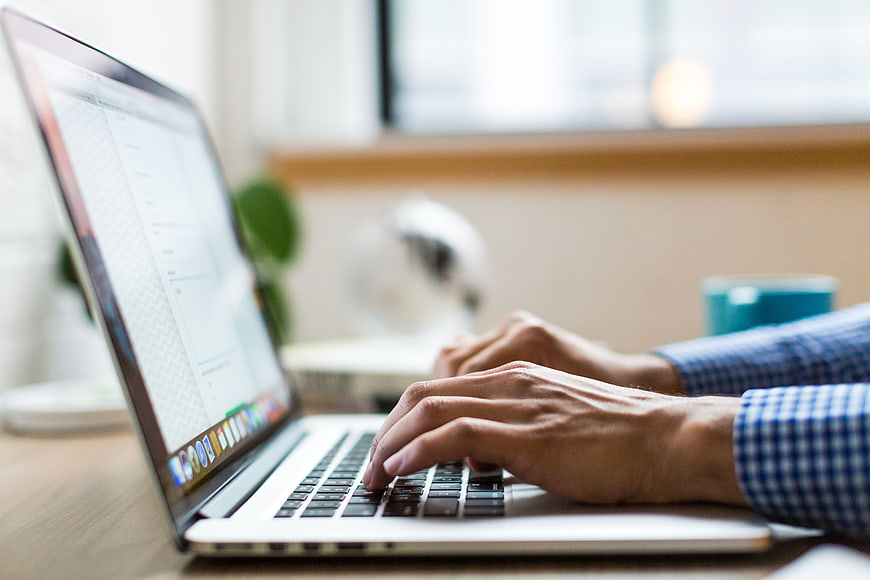 Close-up of hands typing on a laptop keyboard in office