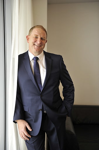 Smiling Businessman in Navy Suit Standing by Window