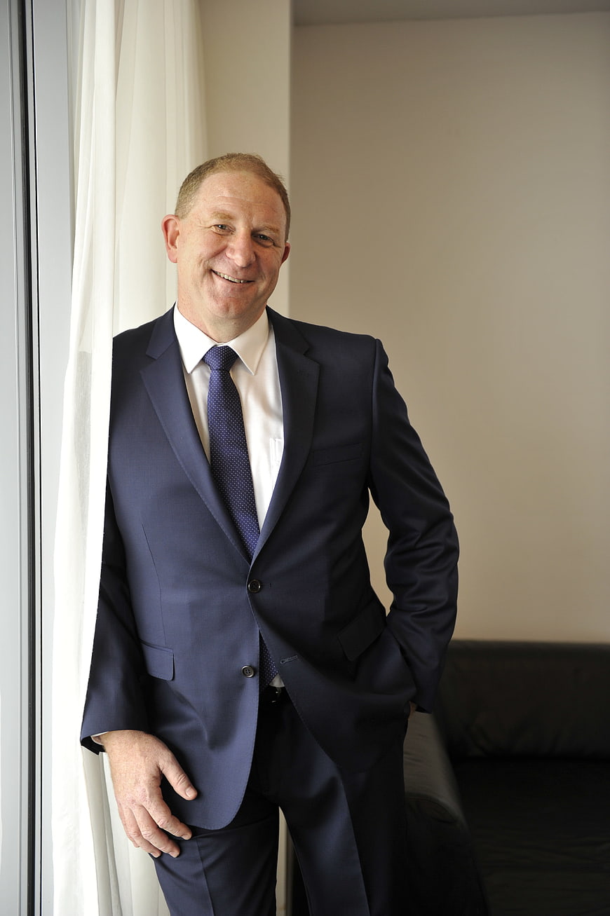 Smiling Businessman in Navy Suit Standing by Window