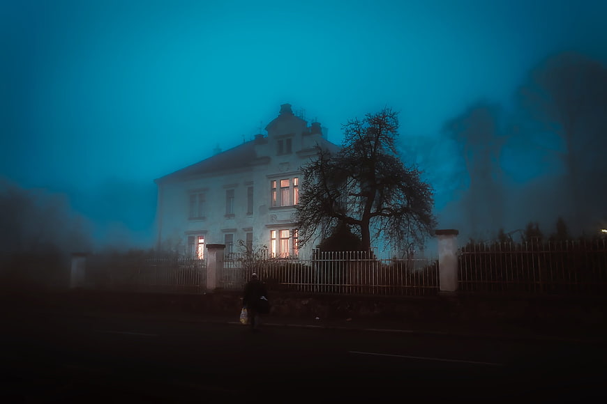 Eerie Blue Mansion in Foggy Night with Walking Silhouette