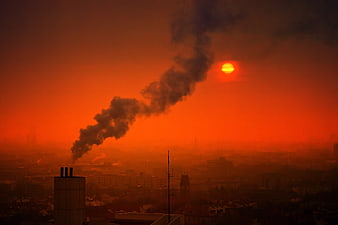 Industrial Smoke Plume Against Red Sunset Over City Skyline