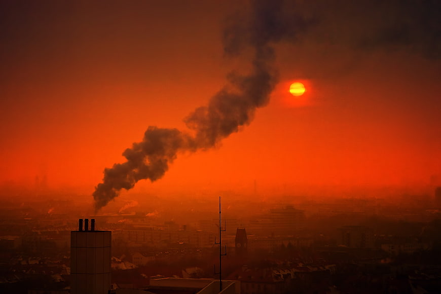 Industrial Smoke Plume Against Red Sunset Over City Skyline