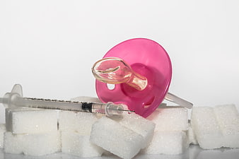 Pink Baby Pacifier, Insulin Syringe, And Sugar Cubes On White Background
