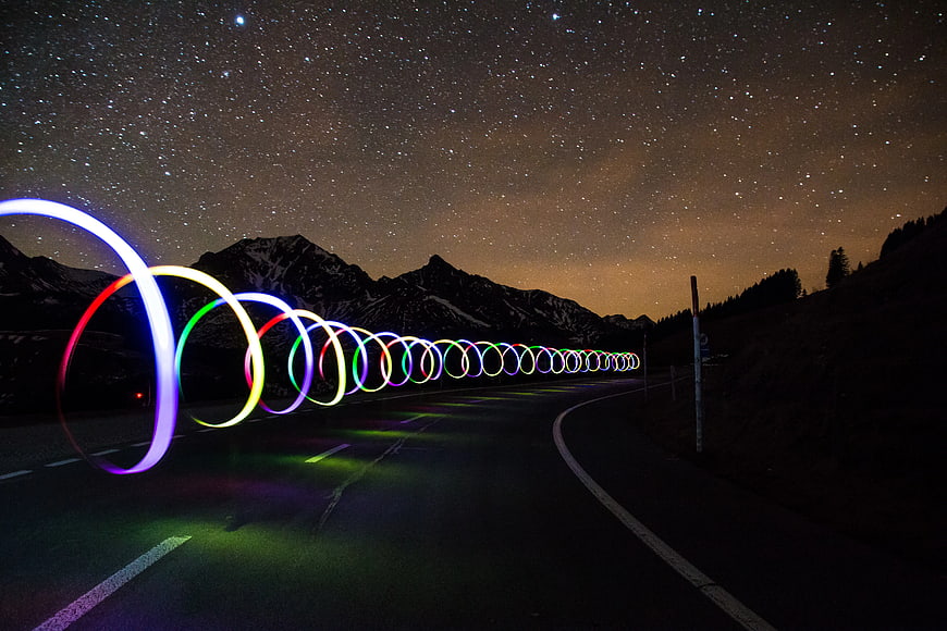 Colorful light painting rings on a mountain road at night