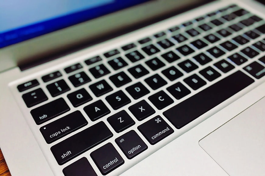 Close-up of Silver Laptop Keyboard on Wooden Desk
