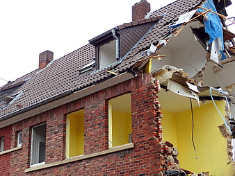Partially Demolished Brick House With Exposed Yellow Walls And Roof Damage