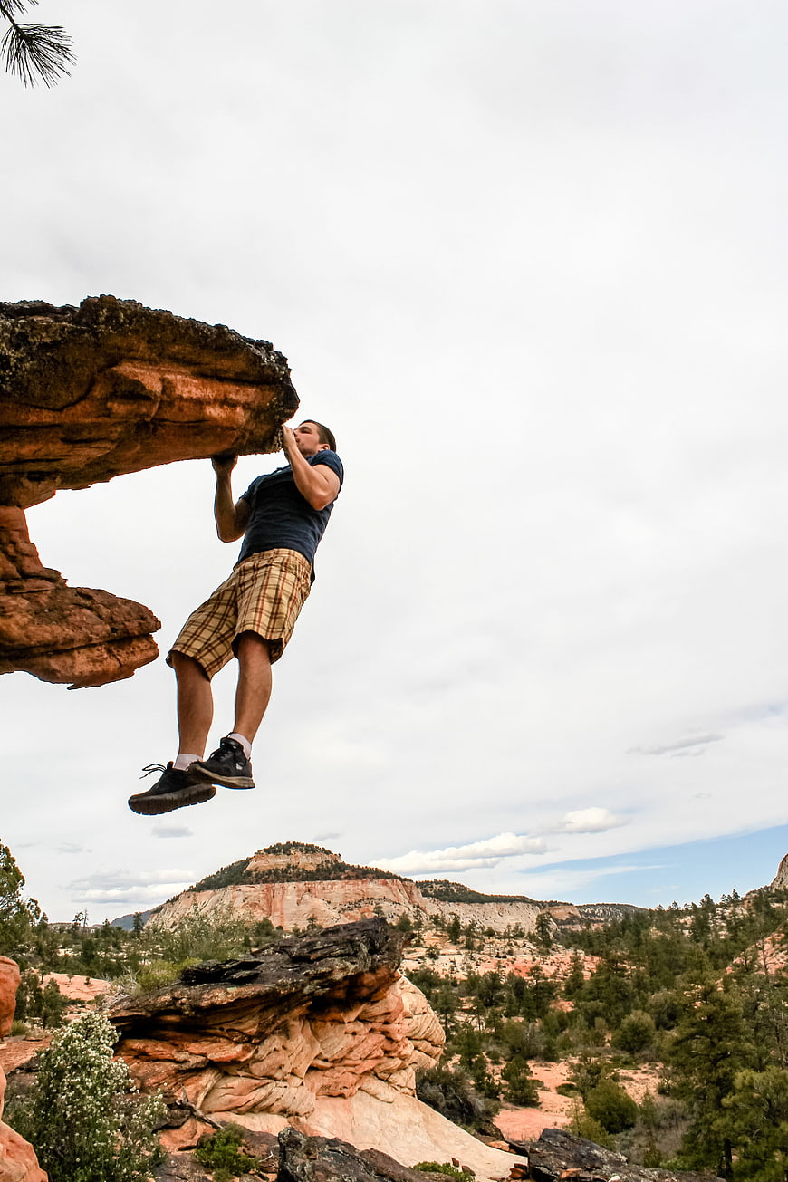 Man bouldering on red sandstone cliff in desert landscape