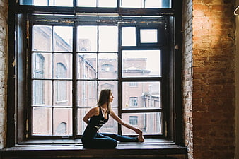 Woman Stretching in Yoga Pose by Large Industrial Window