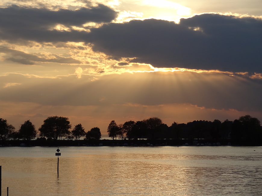 Dramatic sunset sunbeams over a calm lake with silhouetted trees