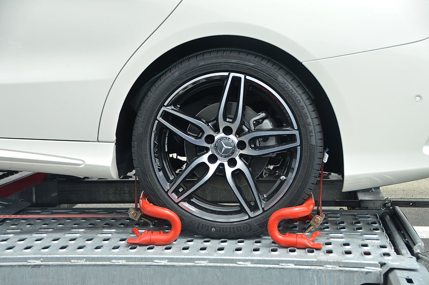 White Mercedes-Benz wheel secured with red wheel clamps on tow truck