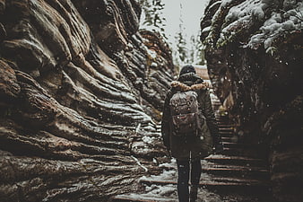 Woman hiking up snowy stone steps in winter canyon