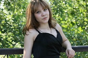 Young woman with bangs leaning on railing outdoors