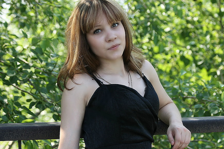Young woman with bangs leaning on railing outdoors