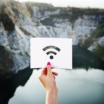 Hand holding wifi symbol card against quarry lake background