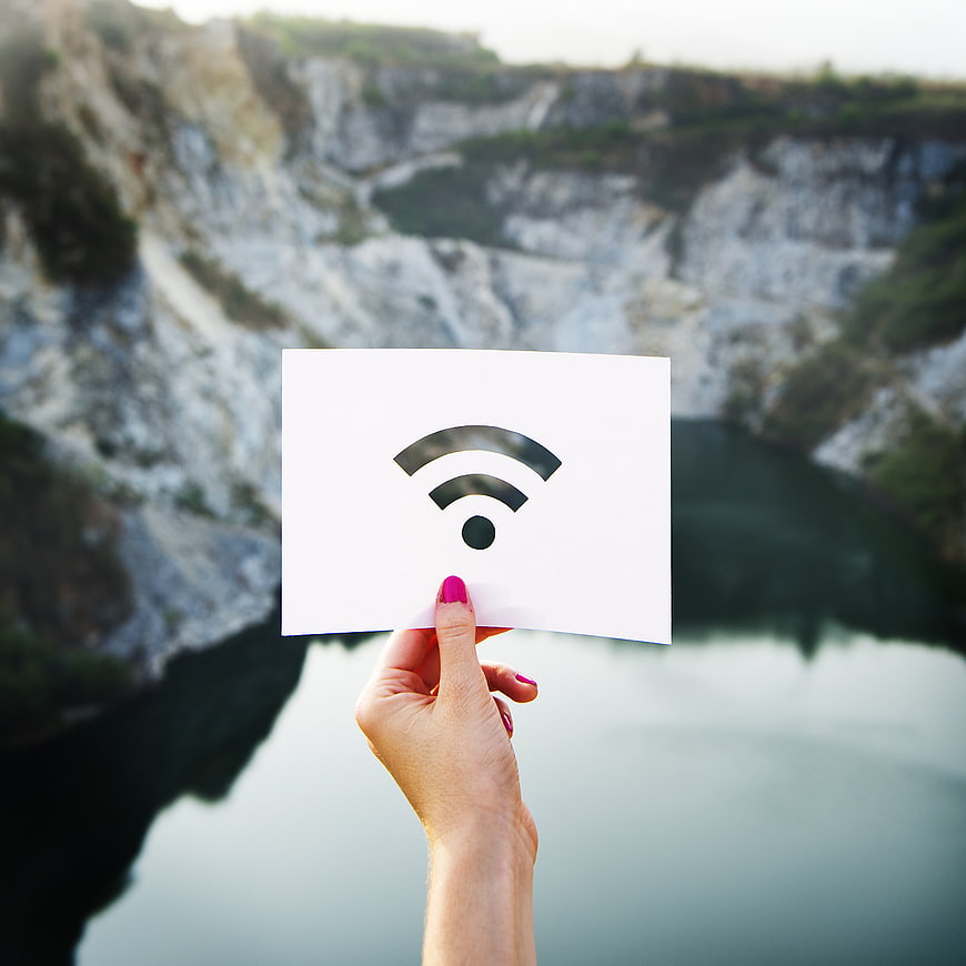 Hand holding wifi symbol card against quarry lake background
